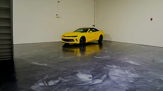 The same metallic floor seen across the bay toward the door, the car parked at the far wall