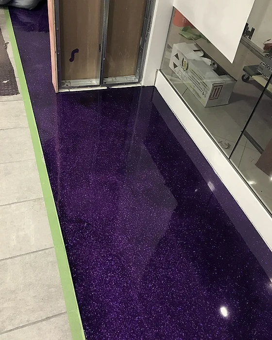 The finished glitter floor running past a shopfront glazing line, its flake catching the store lighting